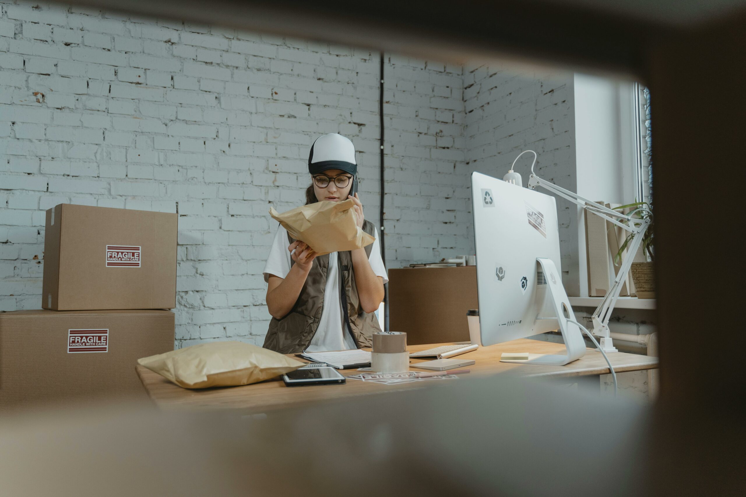 Courier in modern office checking parcel with technology and shipping materials around.
